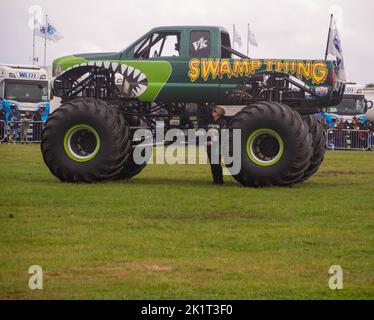 Sumpf-Ding Monster Truck zeigt, wie groß es ist, indem der Partner des Besitzers darunter steht. Stockfoto