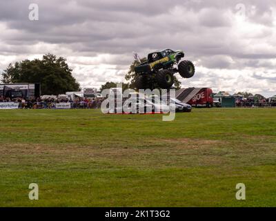 Sumpf-Ding Monster Truck demonstriert seine Fähigkeiten beim Springen über Autos, actiongeladene Fotografie Stockfoto