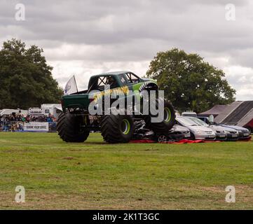 Sumpf-Ding Monster Truck demonstriert seine Fähigkeiten beim Springen über Autos, actiongeladene Fotografie Stockfoto