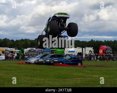 Sumpf-Ding Monster Truck demonstriert seine Fähigkeiten beim Springen über Autos, actiongeladene Fotografie Stockfoto