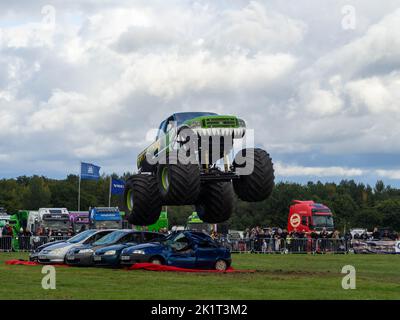 Sumpf-Ding Monster-Truck, der über Autos springt, hat mitten im Sprung actiongeladene Fotos aufgenommen Stockfoto