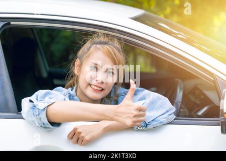 Lady im Auto glücklich lächelnd Daumen hoch Genießen Sie das Fahren mit guten Fahrten. Stockfoto