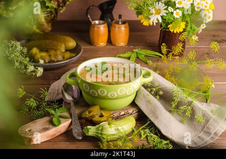 Traditionelle Rassolnik-Suppe mit eingelegten Gurken in einer grünen Terrine auf einem hölzernen Hintergrund Stockfoto