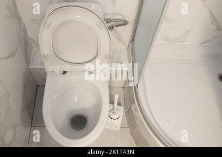 Toilettenschüssel und Duschkabine in einer Wohnwohnung in der Ukraine in hellen Farben, Bad, Innenraum, Blick von oben nach unten Stockfoto