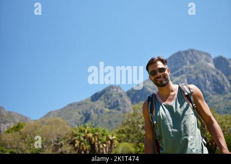 Es ist ein langer Weg nach oben, aber ich bin bereit. Ein Wanderer mit einem Rucksack auf dem Rücken. Stockfoto