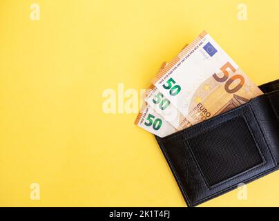 Fünfzig Euro-Banknoten in einer schwarzen Brieftasche auf gelbem Hintergrund, Geldpapierwährung, Zahlung, verdienen und sparen, europäische Währung, Geld und Geld Stockfoto