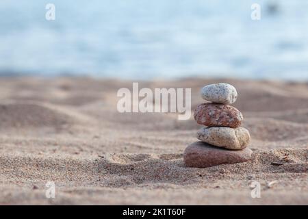 An der Küste liegen runde Steine übereinander in einer Säule Stockfoto