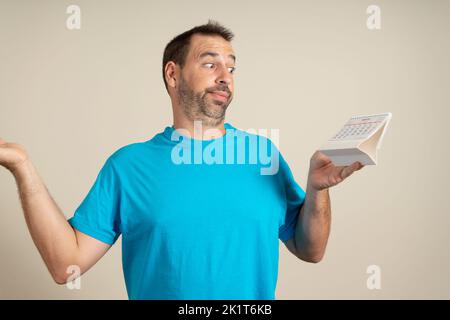 Lateinischer hübscher bärtiger Mann mittleren Alters, der zögert, sich aus dem Gelenk zu lösen, weil sich die Daten nicht summieren. 2022 Kalenderkonzept. Stockfoto