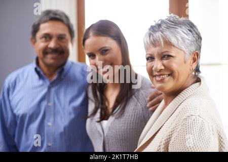 Shes immer noch unser Baby Mädchen. Porträt eines älteren Ehepaars, das mit seiner erwachsenen Tochter zu Hause steht. Stockfoto