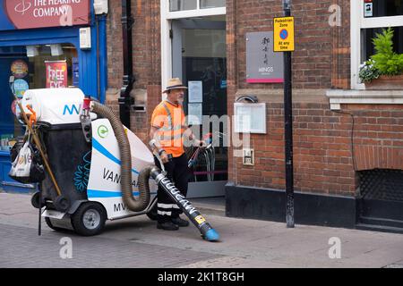 Stadtangestellter reinigt den Bürgersteig mit einem elektrischen kommunalen Abfallstaubsauger in Windsor, Großbritannien Stockfoto