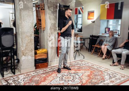 Junger Geschäftsmann mit Mikrofon bei einer öffentlichen Sprechausbildung. Stockfoto