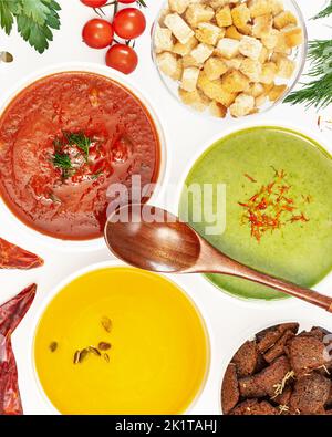 Lebensmittelbanner mit Set verschiedener Gemüsecremesuppen mit Holzlöffel auf weißem Hintergrund mit Zutaten. Gemütliches Essen, vegetarisch gesundes Essen. Stockfoto