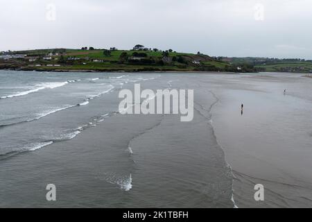 Gezeitenwellen am Inchydoney Beach an einem bewölkten Tag. Ein paar Urlauber am Strand im Süden Irlands. Küstenlandschaft. Der berühmte Strand in der Nähe der Stockfoto