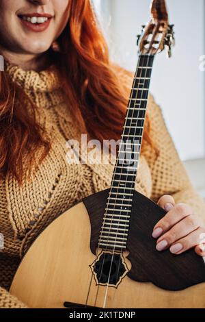 Domra Folk Musikinstrument in weibischer Hand. Weibliche Hände mit 4 Saiten Naturholz Handgefertigtes Musikinstrument Domra Close Up Stockfoto