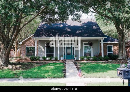 Eine Vorderansicht eines akadischen renovierten Hauses mit Säulen, Gehwegen und einer farbenfrohen Eingangstür, die kürzlich mit dem sich verändernden Immobilienmarkt gekauft wurde Stockfoto