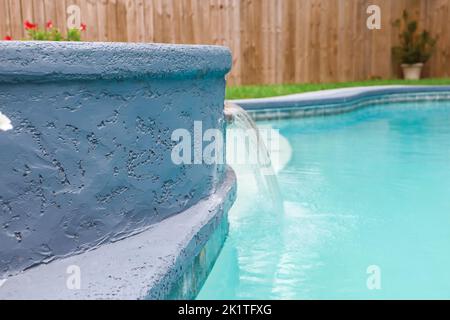 Ein Jacuzzi-Whirlpool neben einem großen Freiform-Swimmingpool mit Wasserfall-Wasserspiel Stockfoto