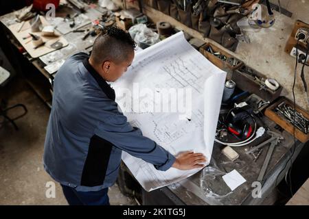 Aus der Perspektive einer Arbeiterin, die Pläne und Pläne in der Werkshalle ansieht, Raum kopieren Stockfoto