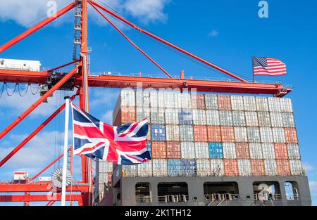 Containerschiff mit britischen und US-amerikanischen Flaggen. Handelsabkommen, Import, Exportzölle... Konzept Stockfoto