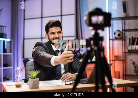 Selbstbewusster, qualifizierter arabischer Händler oder Büroangestellter, der bei Online-Meetings vor der Videokamera sitzt, und Grüße an seinen Kollegen, die Handschlag nachahmen. Stockfoto