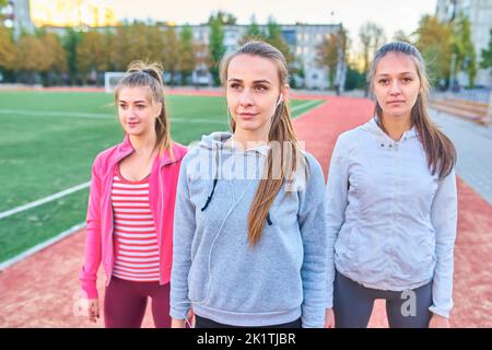 Positive Frauen Sport Übungen.. Die Gruppe der drei schöne junge Frauen, die Sport im sonnigen Tag im Park. Stockfoto