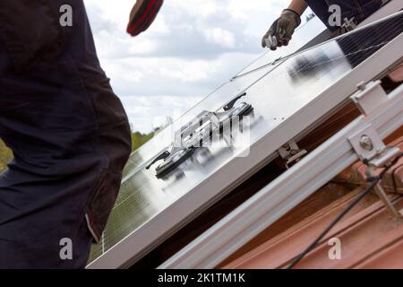 Arbeiter installieren Solarzellen auf dem Dach. Konzept für alternative Energien. Stockfoto