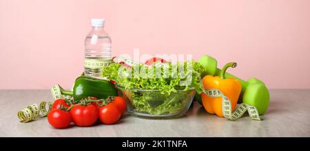 Verschiedene gesunde Lebensmittel mit Messband und Hanteln auf dem Tisch. Diät-Konzept Stockfoto