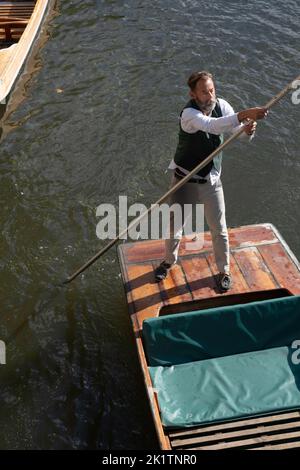 Mann mit einer grünen Weste von 'Cambridge Chauffeur Punts', der auf der River Cam in Cambridge puntiert. Von oben gesehen Stockfoto