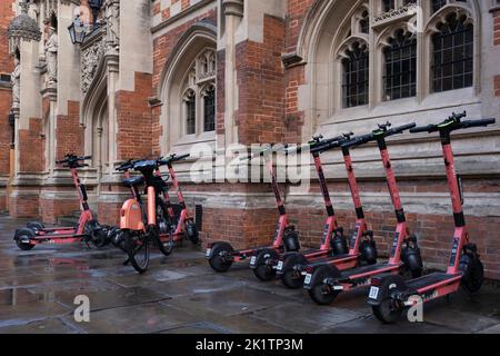 Geteilte E-Scooter oder E-Steps der Firma VOI zur Miete warten im Regen auf Kunden in einer Straße in Cambridge. E-Mobilität Stockfoto