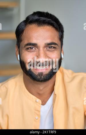 Glücklich lächelnder indischer Mann, der drinnen auf die Kamera schaut. Nahaufnahme des vertikalen Hochformatbildnisses. Stockfoto
