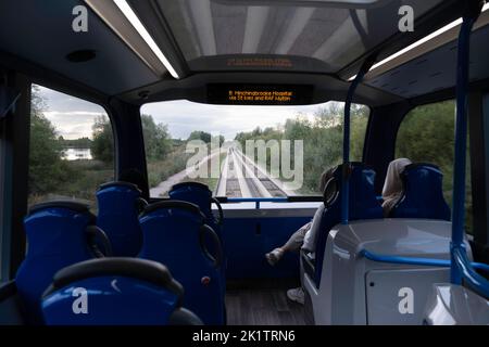 Blick durch das obere Fenster eines Cambridgeshire Doppeldeckerbusses vom Guided Busway aus. Die Streckenspuren sind deutlich sichtbar. Konzentrieren Sie sich auf den entgegenkommenden Bus Stockfoto