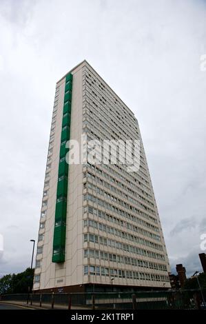 Hoher Wohnturm unter bewölktem Himmel in London mit modernistischer Nachkriegsarchitektur mit grünen Renovierungsplatten an der Fassade Stockfoto