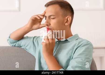 Junger Mann mit Nasenbluten und Gewebe zu Hause Stockfoto