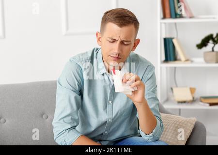 Junger Mann mit Nasenbluten und Gewebe zu Hause Stockfoto