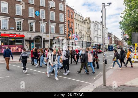 Fußgänger, die eine Straße mit einer Fußgängerüberführung im Stadtzentrum von Dublin, Irland, überqueren. Stockfoto