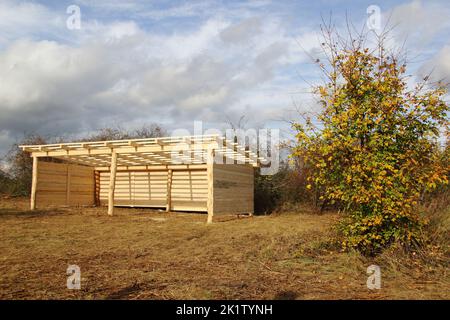 Holzställe - Unterstand für domestizierte Tiere auf einer Weide in der freien Natur Stockfoto