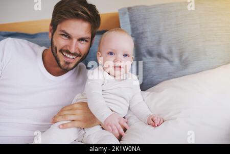 Ich halte sie immer nahe. Beschnittenes Porträt eines jungen Vaters und seiner kleinen Tochter im Schlafzimmer. Stockfoto