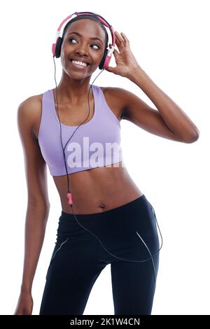 Das ist ihr Favorit. Eine glückliche junge Frau in Sportkleidung, die mit ihren Kopfhörern Musik hört. Stockfoto