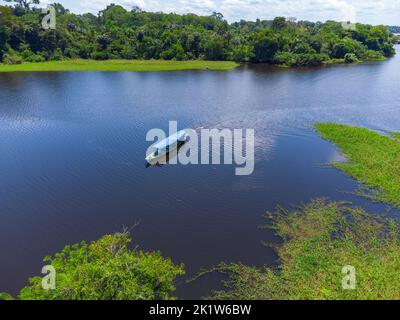 Ein kleines Boot fährt im amazonas mitten im Regenwald Brasiliens, Luftaufnahme Stockfoto