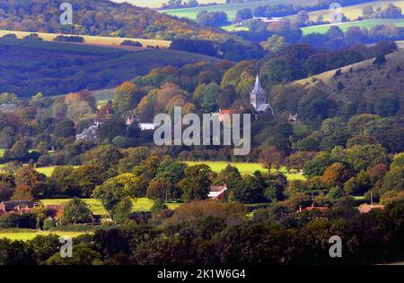 Die Farben des Herbstes umhüllen das Dorf East Meon in der Nähe von Petersfield, Hampshire, in der Morgensonne. Die Allerheiligen-Kirche aus dem 12.. Jahrhundert ist von Bäumen aller Schattierungen umgeben, bevor sie im Herbst ihre Blätter verlieren. Pic Mike Walker,2014 Mike Walker Pictures Stockfoto