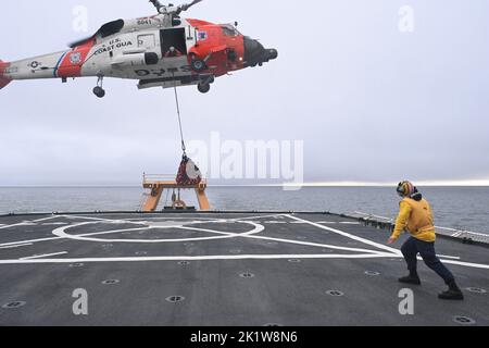 Eine Flugbesatzung des Hubschraubers Kodiak MH-60 Jayhawk von der Luftstation hebt während einer vertikalen Nachschubübung (VERTREP) von der Küstenwache-Schneidevorrichtung Healy (WAGC 20) in Kotzebue Sound, Alaska, 7. September 2022 ab. Der Landeanzeiger-Offizier, Ensign Luke Monaco, leitet den Flugbetrieb auf dem Flugdeck der Healy. (USA Foto der Küstenwache von Deborah Heldt Cordone, Fachkraft für öffentliche Angelegenheiten 1) Stockfoto