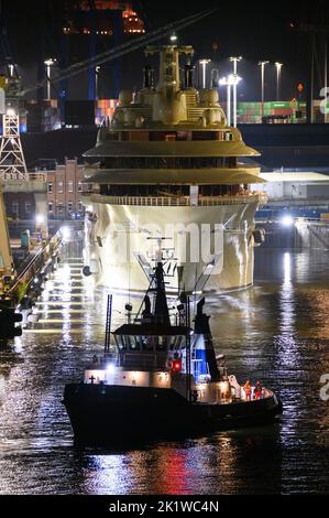 Hamburg, Deutschland. 21. September 2022. Die Luxusyacht 'Dilbar' liegt im Dock hinter einem Schlepper. Die 'Dilbar' wird von Schleppern aus dem überfluteten Trockendock der Werft Blohm Voss auf die Elbe vor den Landungsbrücken geschleppt. Um das Trockendock 'Elbe 17' in Hamburg für die Reparatur anderer Schiffe freizumachen, wird die Yacht ohne eigene Motorleistung per Schlepper zu einem anderen Liegeplatz in Bremen geschleppt. Die Luxusyacht „Dilbar“ wurde im April 2022 aufgrund von EU-Sanktionen aufgrund der Invasion russischer Truppen in der Ukraine festgenommen. Quelle: Jonas Walzberg/dpa/Alamy Live News Stockfoto