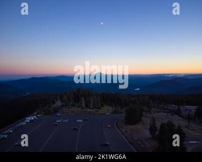 Großer Asphaltparkplatz im Wald. Berge sind in der Ferne sichtbar. Dämmerung. Schießen von einer Drohne. Schöne Panoramaaufnahme. Ökologie, Reisen, To Stockfoto