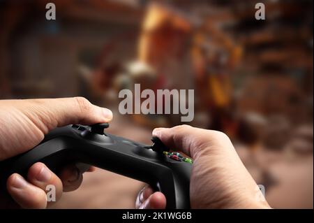 Ein Spieler mit einem Joystick in den Händen spielt ein Videospiel auf dem Bildschirm eines großen Fernsehers. Nahaufnahme. Online-Spiele, Kommunikation, Spiele mit Freunden online Stockfoto