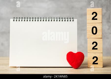 2022 Würfel mit roter Herzform und leeres Notizbuch auf dem Tisch für Ihren Text. Neujahr, Auflösung, Ziel, Plan, Gesundheit, Love and Happy Valentine Day Konz Stockfoto