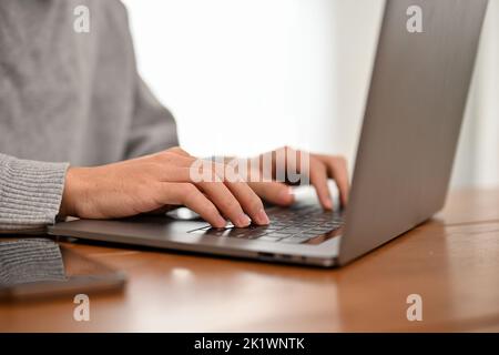 Ein männlicher Student oder Geschäftsarbeiter, der an seiner Online-Arbeit arbeitet, Laptop-Computer benutzt, auf der Tastatur tippt. Nahaufnahme Hände Bild. Stockfoto