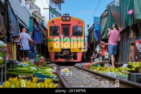 Maeklong Railway Market Thailand, . Trainieren Sie auf der Bahn langsam. Regenschirm Frischmarkt auf der Railroad Track, Mae Klong Bahnhof, Bangkok, Thailand an einem sonnigen Tag Stockfoto