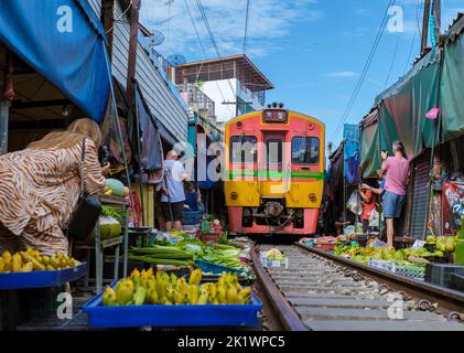Maeklong Railway Market Thailand, . Trainieren Sie auf der Bahn langsam. Regenschirm Frischmarkt auf der Railroad Track, Mae Klong Bahnhof, Bangkok, Thailand an einem sonnigen Tag Stockfoto