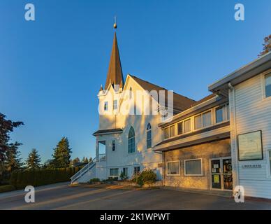 Weiße Holzkirche bei Sonnenuntergang in der Landschaft. Lutherische Kirche in British Columbia Surrey Kanada-September 18,2022. Reisefoto, niemand, Platz zum Kopieren Stockfoto