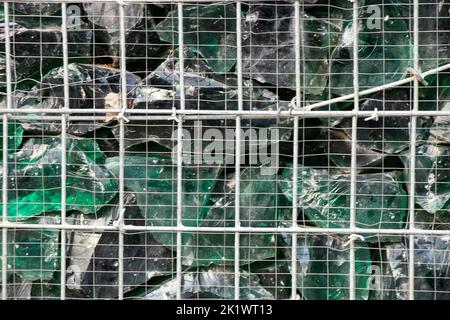 Gabionenzaun aus grünen Glassteinen in den Karpaten in der Ukraine als Hintergrund, Gitterzaun mit Steinen Stockfoto