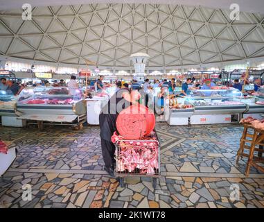 Ein Arbeiter leert Knochen und Fleisch in einen Wagen. Auf dem Chorsu-Markt, Basar in Taschkent, Usbekistan. Stockfoto